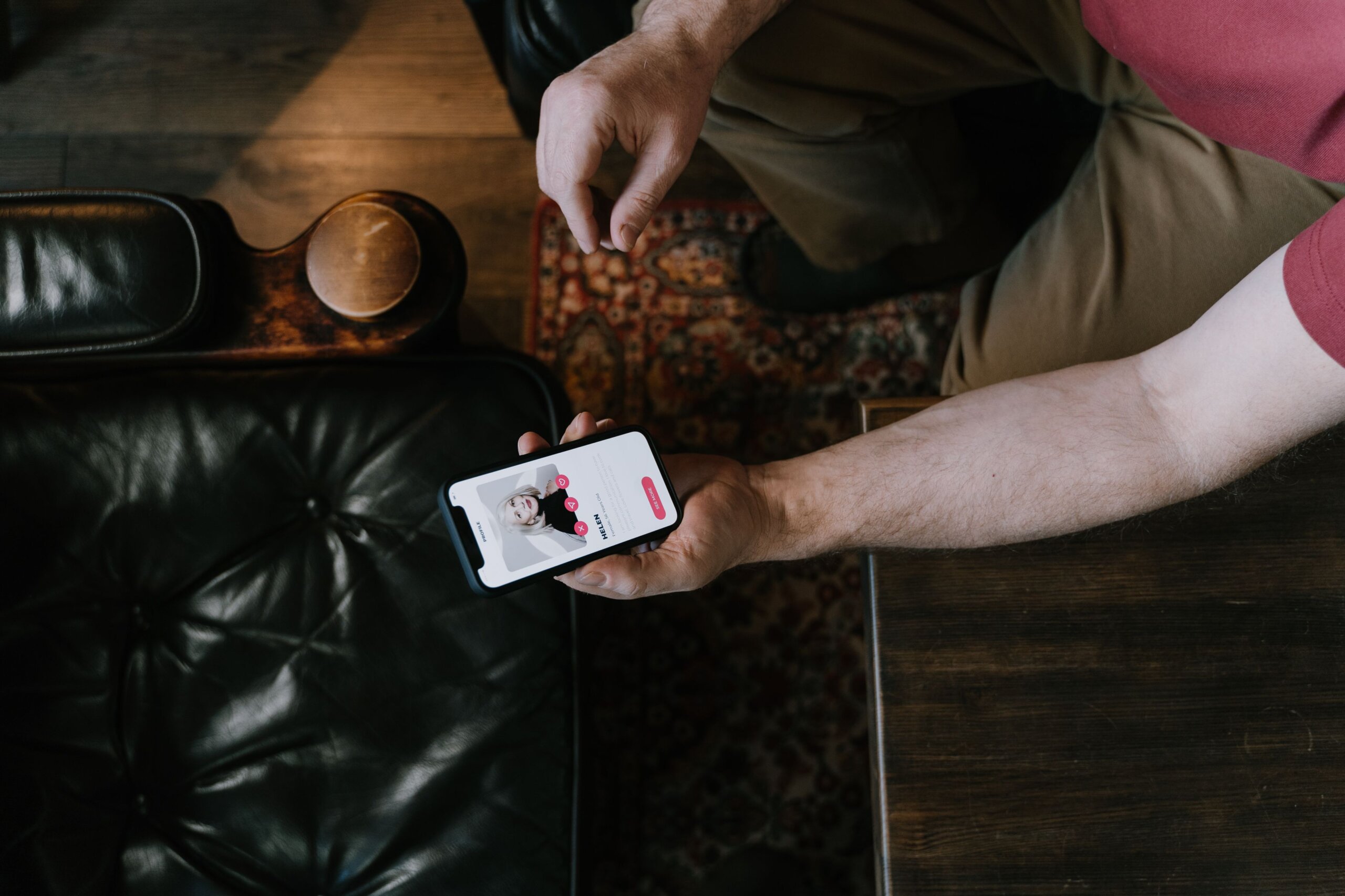 Person holding a smartphone displaying a dating app while seated