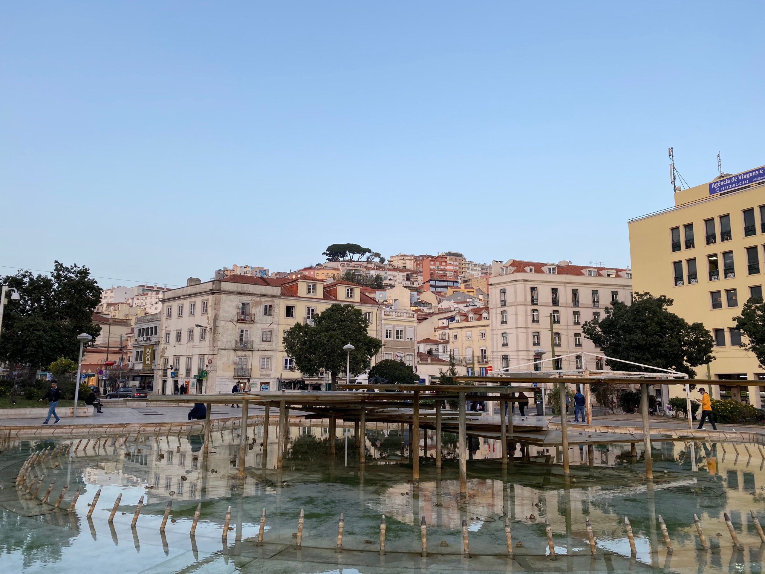 Picturesque Lisbon town square with buildings and reflecting fountain under a clear sky