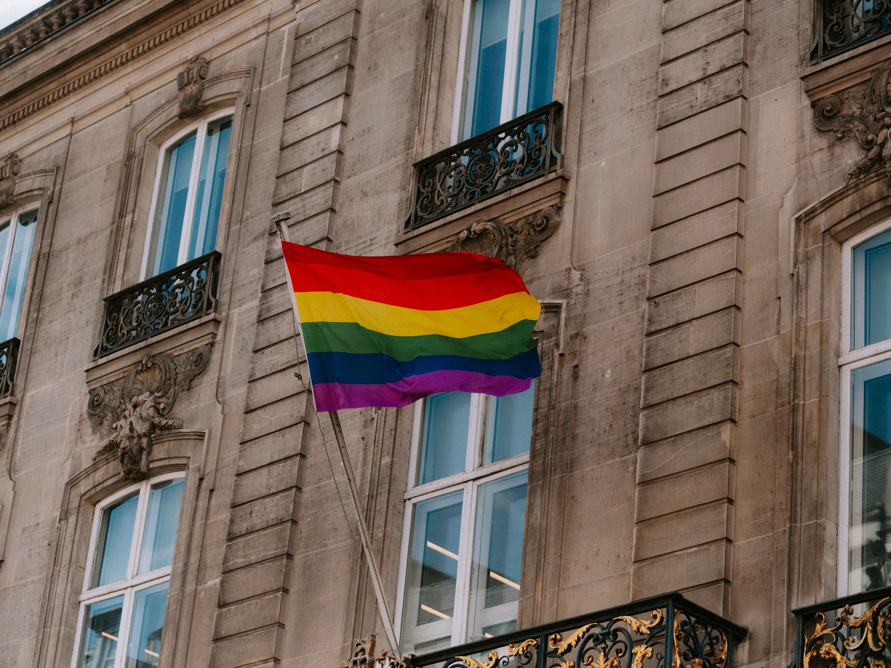 Rainbow pride flag waving in front of a historic Dutch building, marking 25 years of marriage equality in the Netherlands