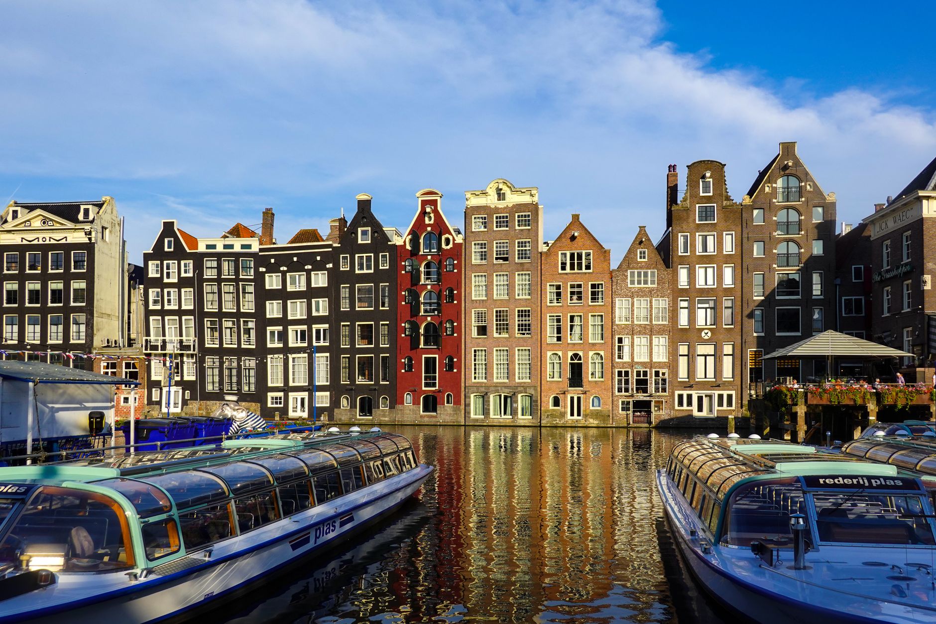 Historic Amsterdam canal with boats and gabled buildings, the route of the WorldPride 2026 Canal Parade