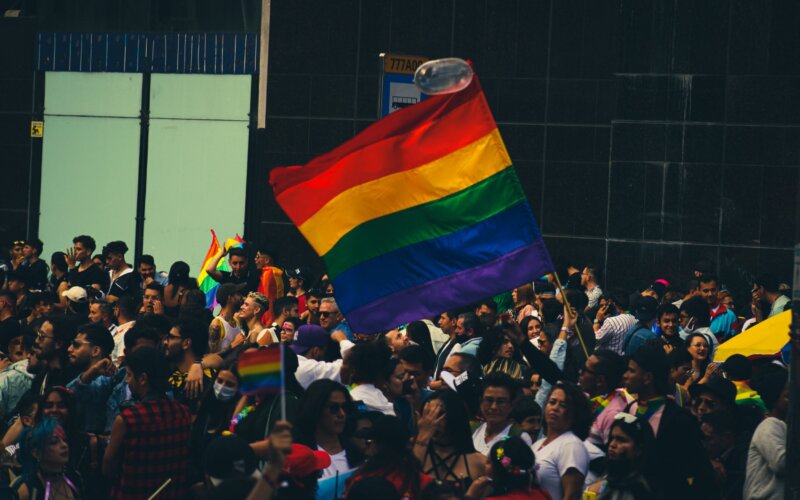 Lively crowd celebrating at a Pride parade with vibrant rainbow flags, Bear Pride Lisbon