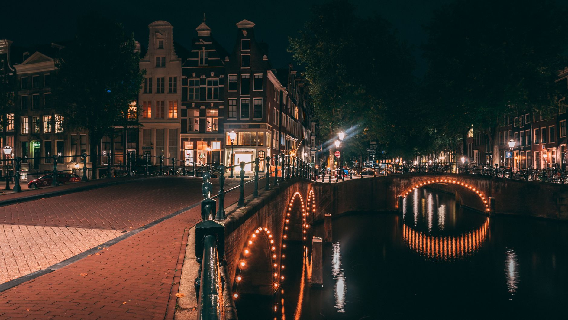 Amsterdam canal at night with amber street lamp light reflecting on water