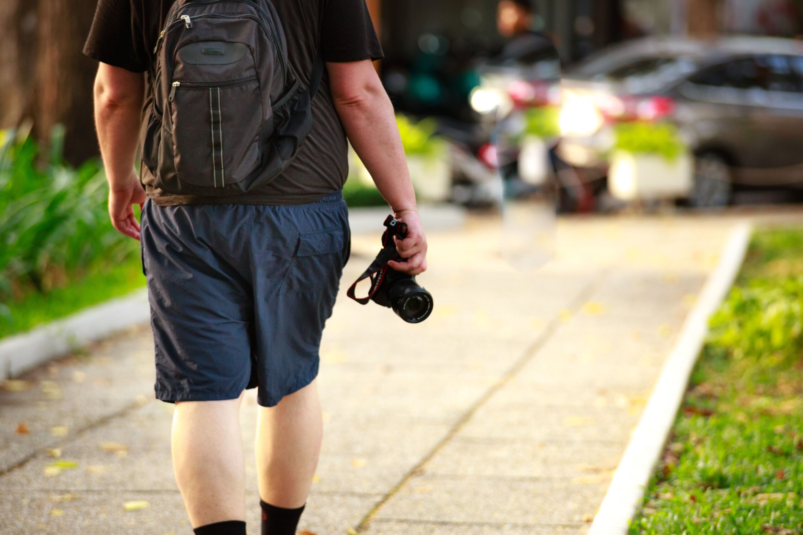Man walking outdoors with a camera and backpack on a sunny day, solo travel in Lisbon
