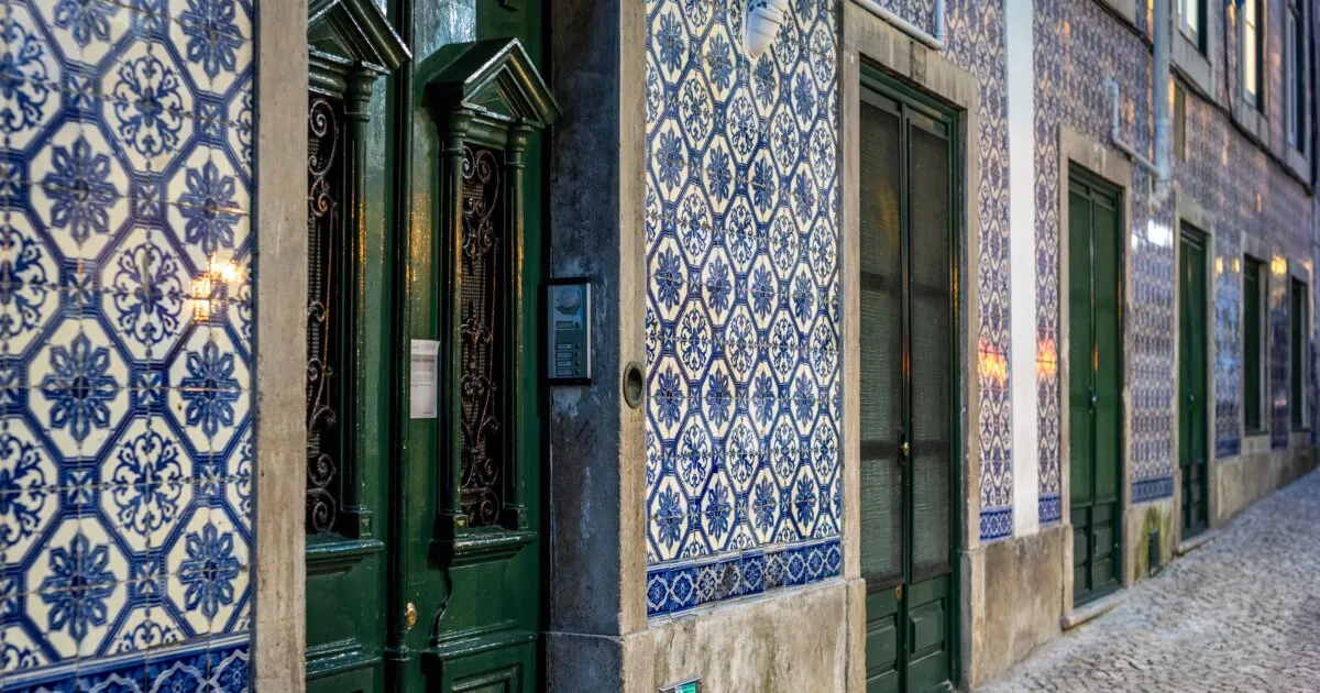 Picturesque street in Lisbon with iconic blue and white Portuguese azulejo tiles and green doorways