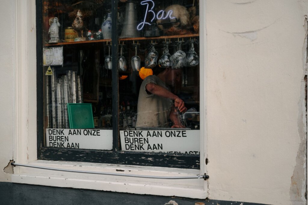 Amsterdam bar window with glasses and signage reflecting urban nightlife charm