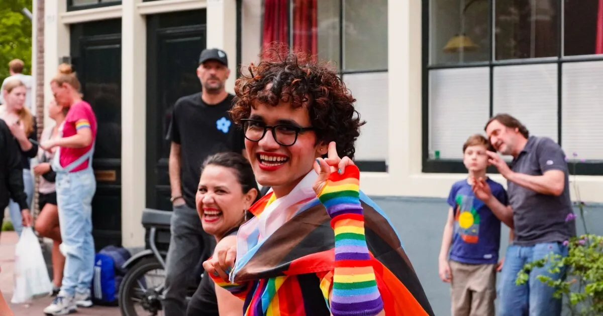 Joyful participants at Amsterdam Pride celebrating in rainbow outfits during WorldPride 2026