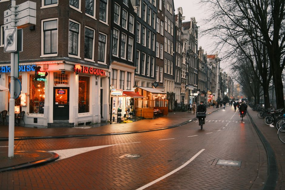 Amsterdam street at dusk with cyclists near De Oeverlanden — amsterdam cruising safety oeverlanden 2026 context