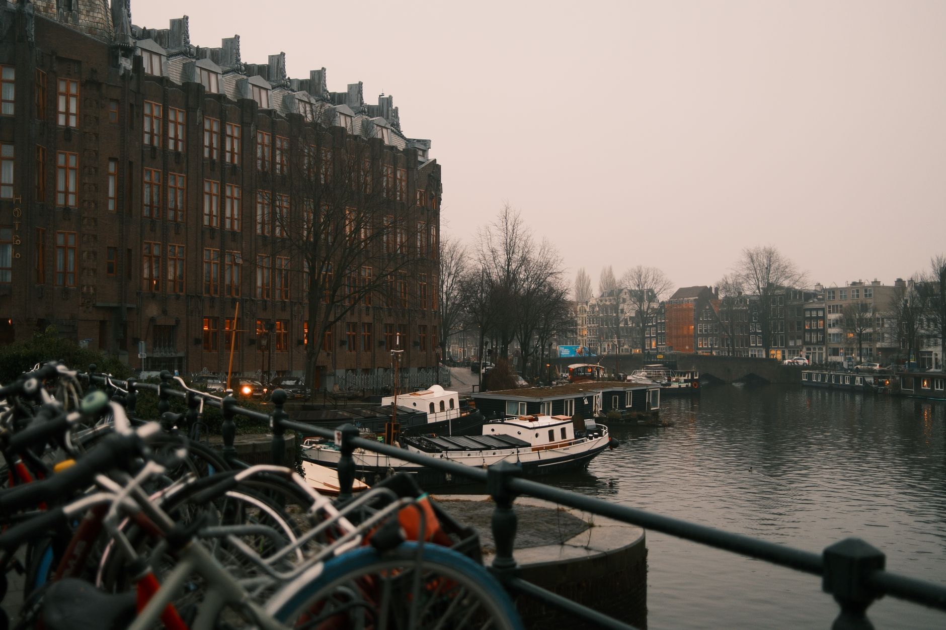 Amsterdam canal at dusk in winter with foggy atmosphere and warm lights on water