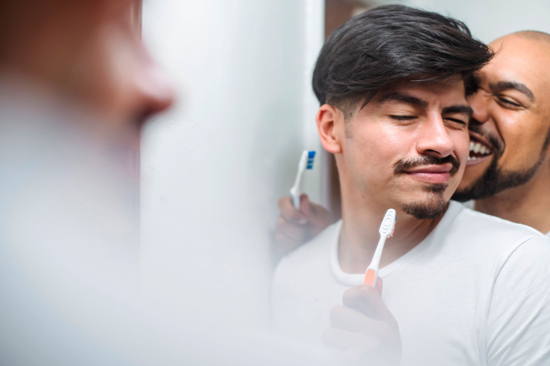 Cheerful same-sex couple sharing a playful moment in their morning routine