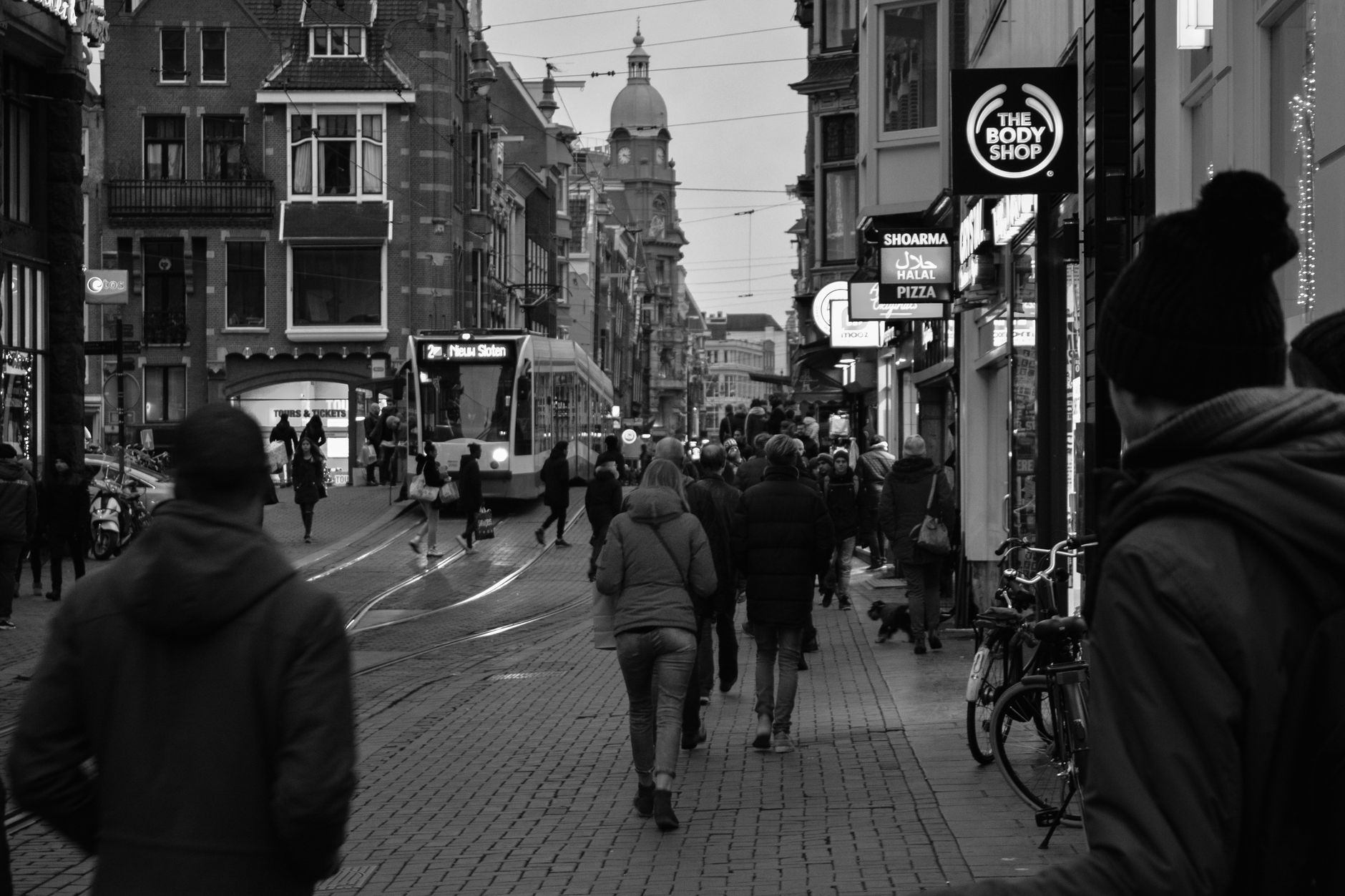 Amsterdam street with pedestrians and tram, local urban life showing the mix of locals and tourists
