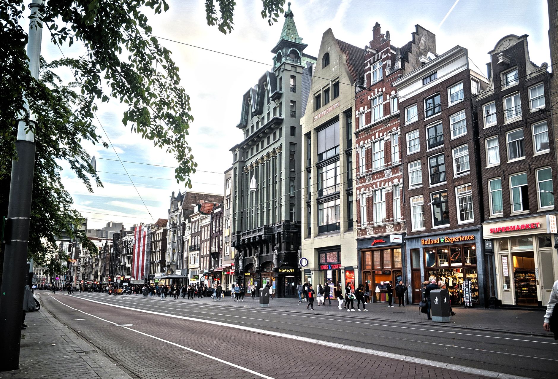 Scenic view of a busy Amsterdam street with historic architecture, capturing the city's local and visitor energy